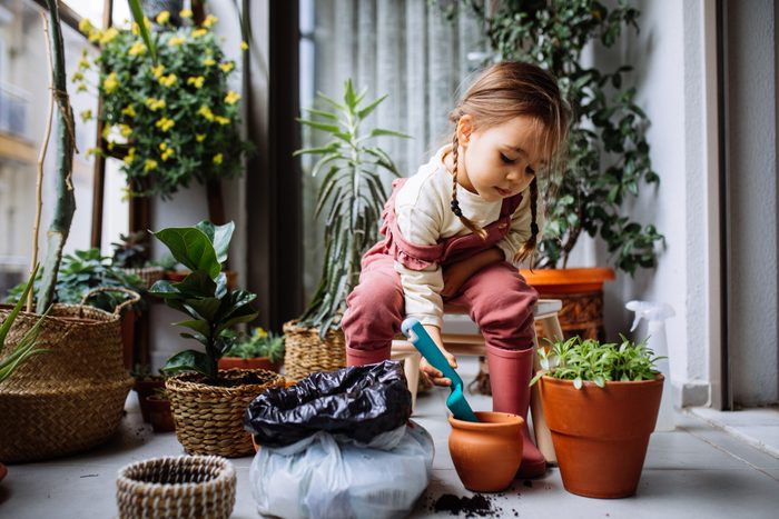 Cute Girl Planting Flowers In House Balcony