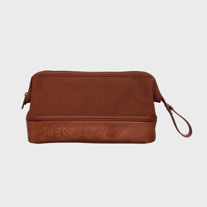 Brown toiletry bag rests on white background, featuring a zipper closure and side strap; brand name 