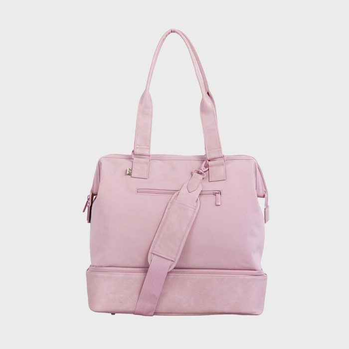 A pink tote bag with two straps and a detachable shoulder strap rests against a plain, white background.