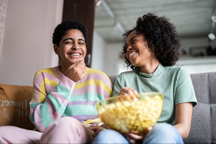 Friends watching TV and eating popcorn at home