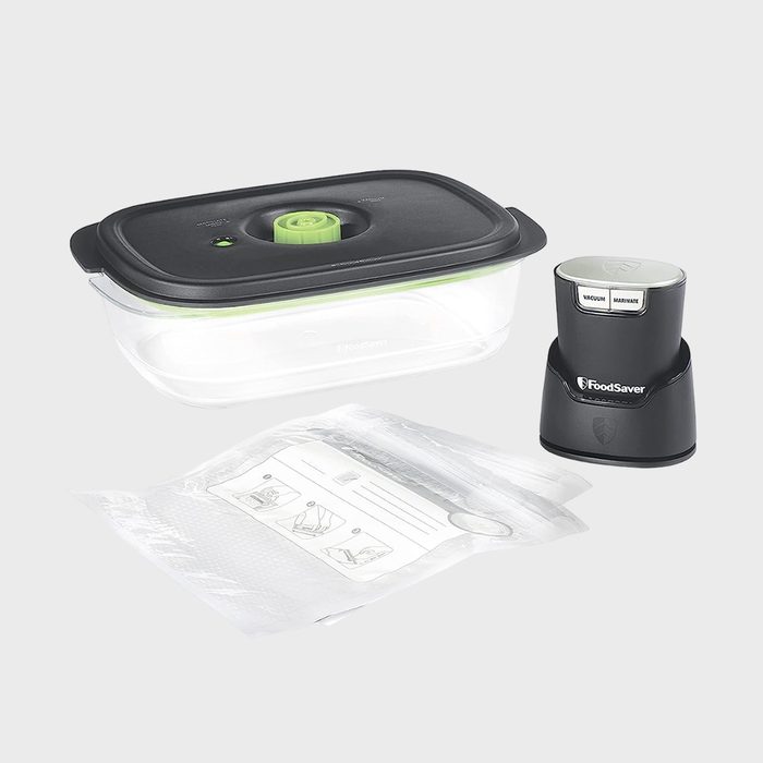 Vacuum sealer kit, including a black-lid container, sealer device, and vacuum bags with instructions, set against a plain background.