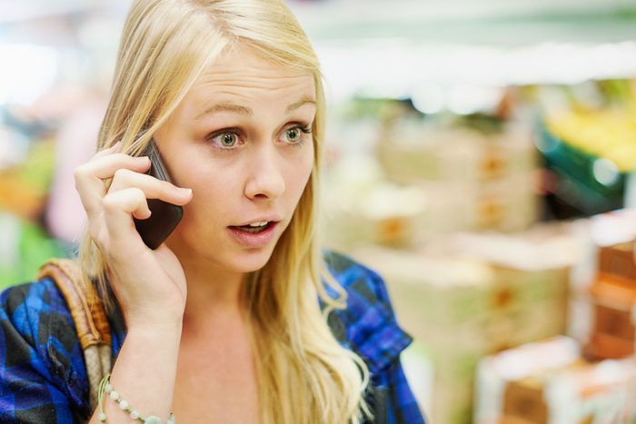 Beautiful young blonde woman, listening to her cellphone, gets some surprising or shocking news
