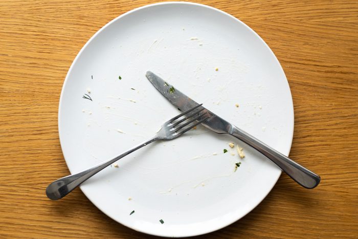 A dirty empty plate, fork and knife on a wooden table