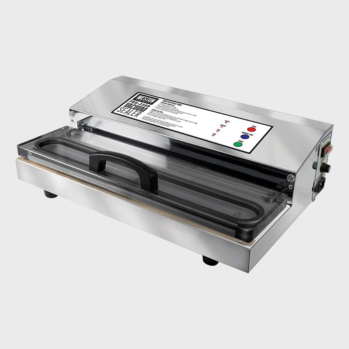 Stainless steel vacuum sealer; lid open, revealing sealing chamber; control panel with buttons; situated on a plain surface.