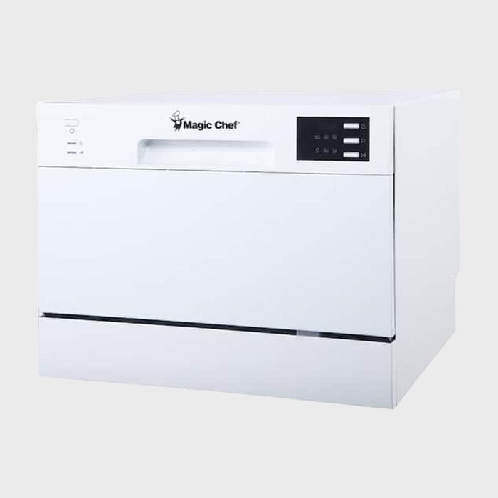 White tabletop dishwasher displays controls; sits in a minimal studio setting. Brand 'Magic Chef' logo on the front panel.