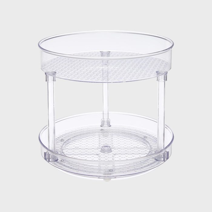 A clear, two-tiered circular organizer with perforated surfaces stands in a neutral, plain background.