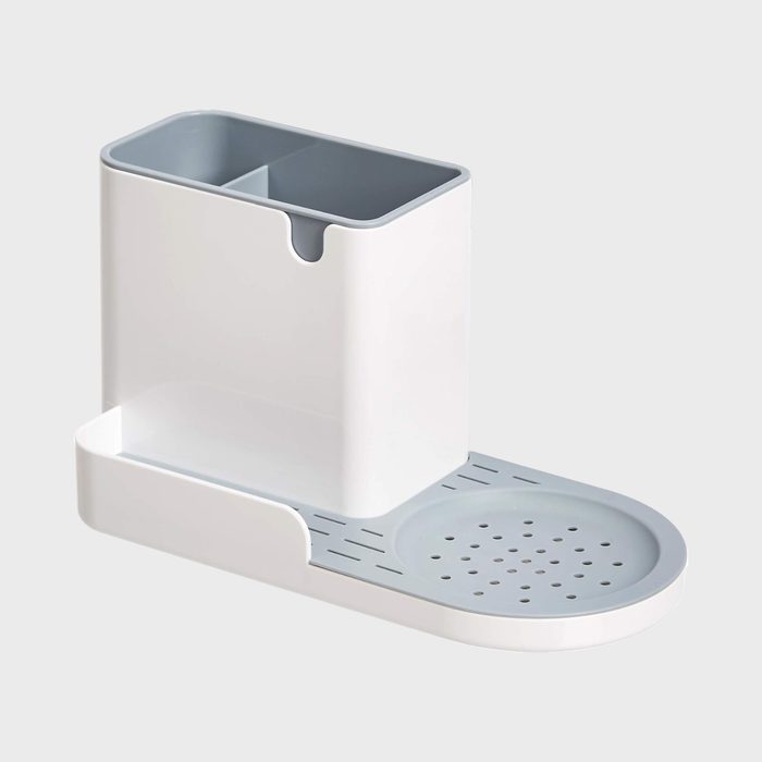 White utensil holder with two compartments sits on a horizontal base featuring a circular draining section, all against a plain gray background.