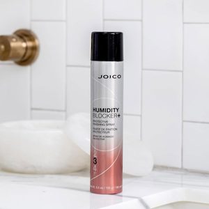 Spray can stands on a marble counter in a white-tiled bathroom. Text reads, 