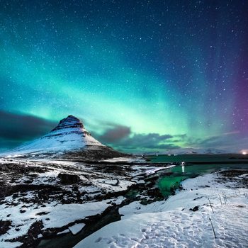 Mountain sits beneath vibrant northern lights, surrounded by snowy landscape and starry sky, with a river winding through the scene.