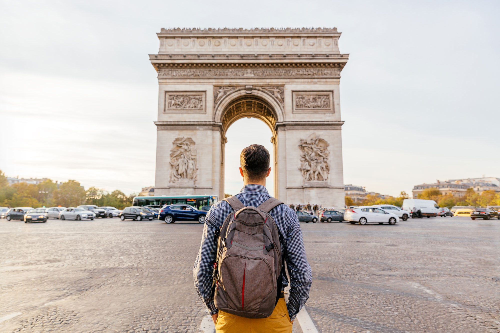 Tourist With Backpack Walking Towards Arc De Triomphe In Paris France