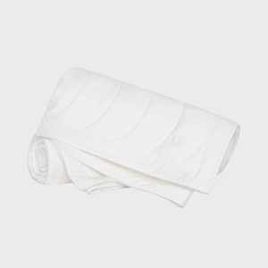 Quilted white duvet, partially rolled up, lies on a plain, light gray background.