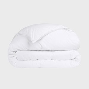 White duvet lays folded upon itself, smooth and bulky, against a plain light grey background.