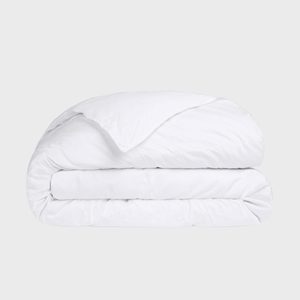 A thick, white duvet lies neatly folded against a plain, light gray background.