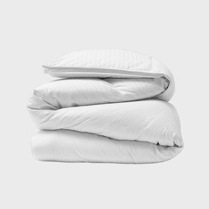 A neatly folded white duvet rests on a plain, light grey background.