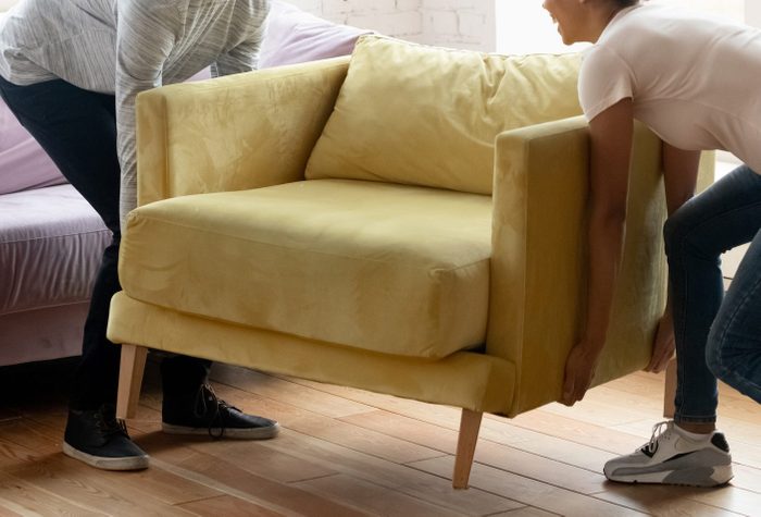 African couple placing new modern armchair in light living room