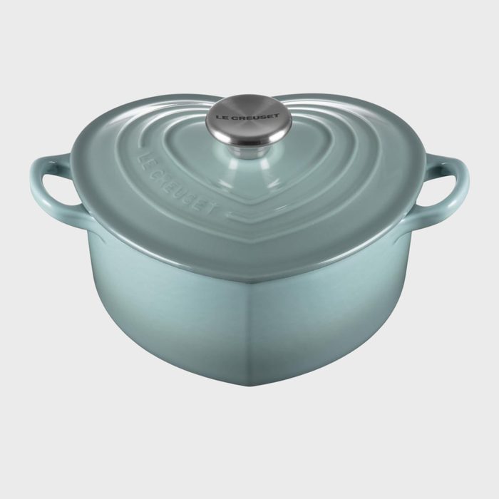 Heart-shaped light blue pot resting, with handles, on a plain background. Lid reads 