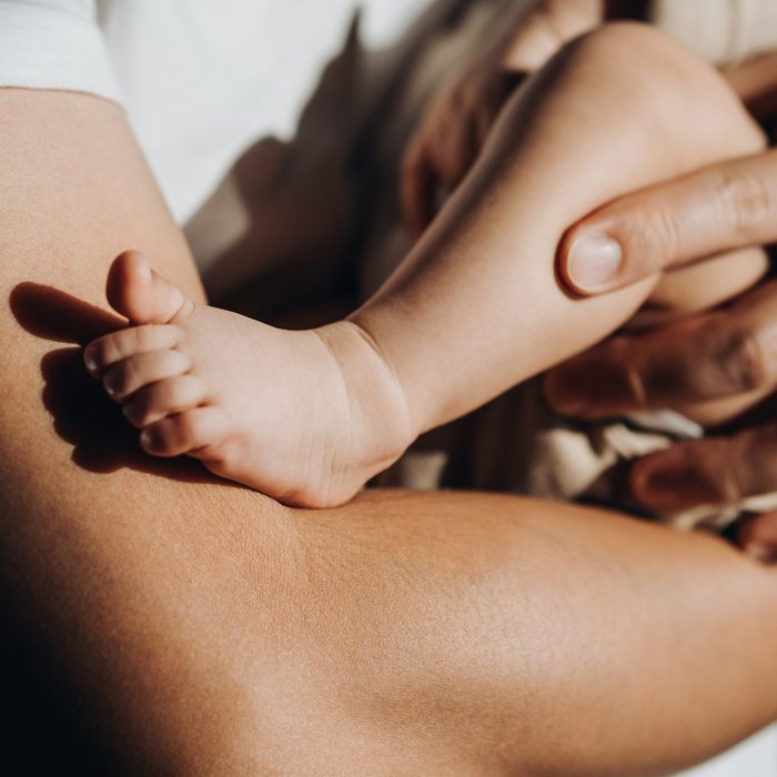 Close up of a loving young Asian father carrying his newborn baby daughter in arms. Bonding moment of father and daughter. Fatherhood. Skin to skin contact. Love, care and tenderness