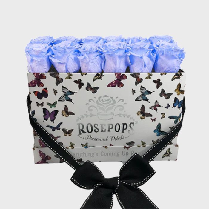 Purple roses sit in a butterfly-patterned box labeled 