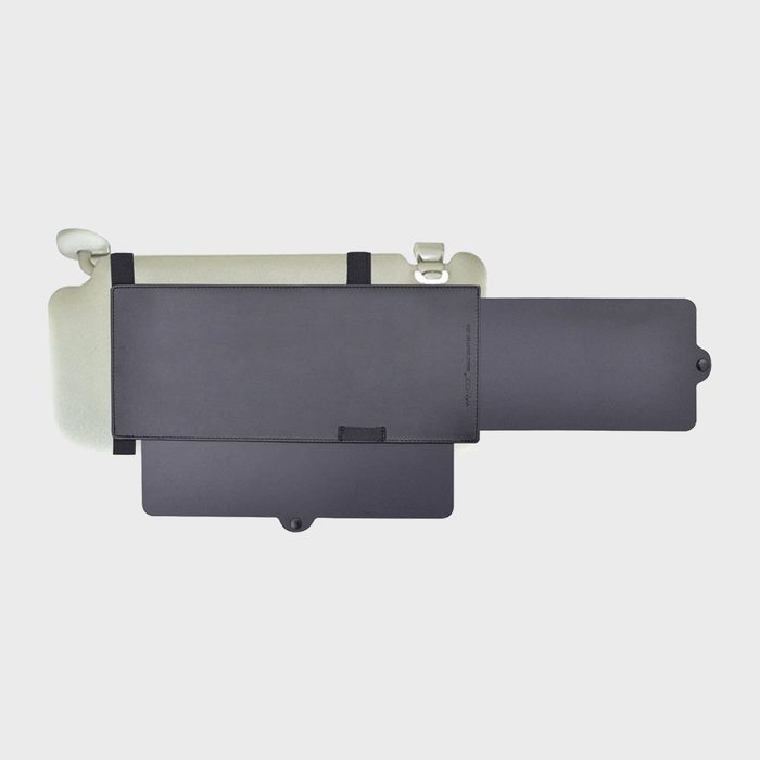 A grey car sun visor extension slides open, attached with black straps in a neutral light setting.