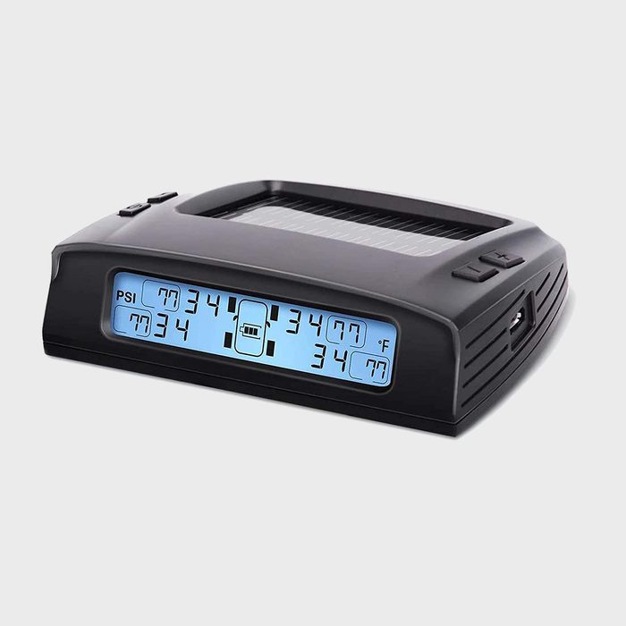 Device displays tire pressure and temperature; shows numbers on screen. Black casing features buttons; solar panel on top. Gray background.