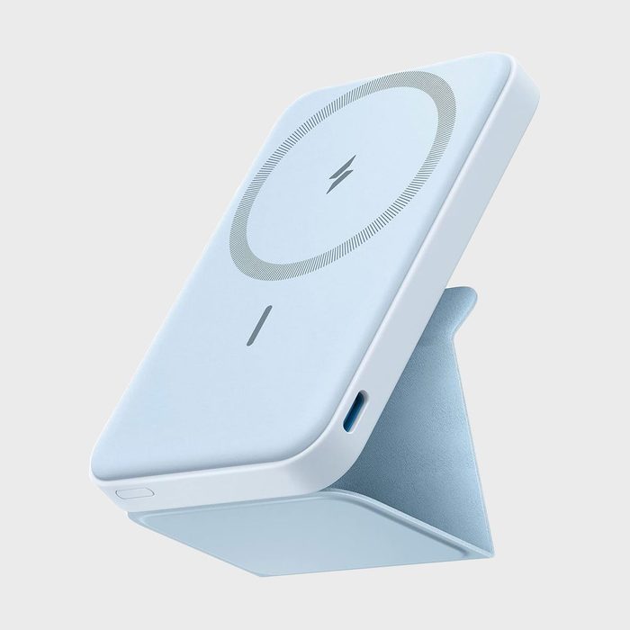 A blue, rectangular, portable charger stands upright with a visible charging symbol, set against a plain gray background.
