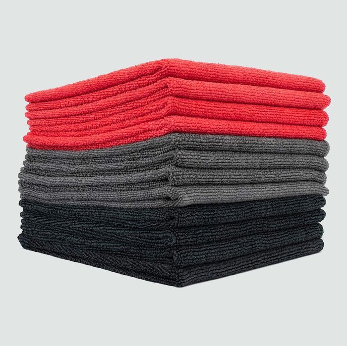 A stack of microfiber towels sits organized in three colored layersâ€”red, gray, and blackâ€”against a plain light background.