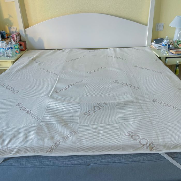 Mattress cover lays flat on a bed displaying brand names 