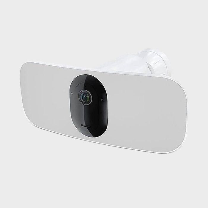 A white security camera with an oval lens protrudes from the center, positioned against a plain grey background.