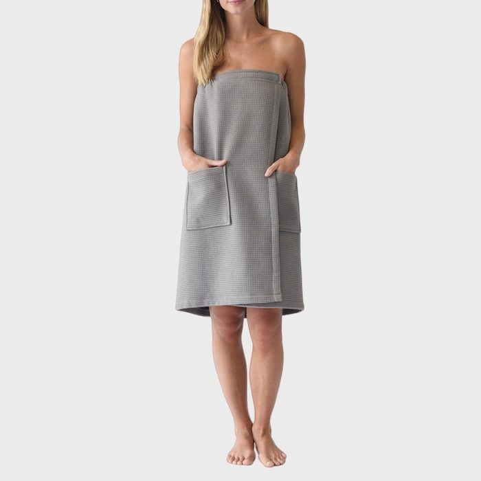 A person wears a grey, textured towel with pockets, standing on a plain white background.