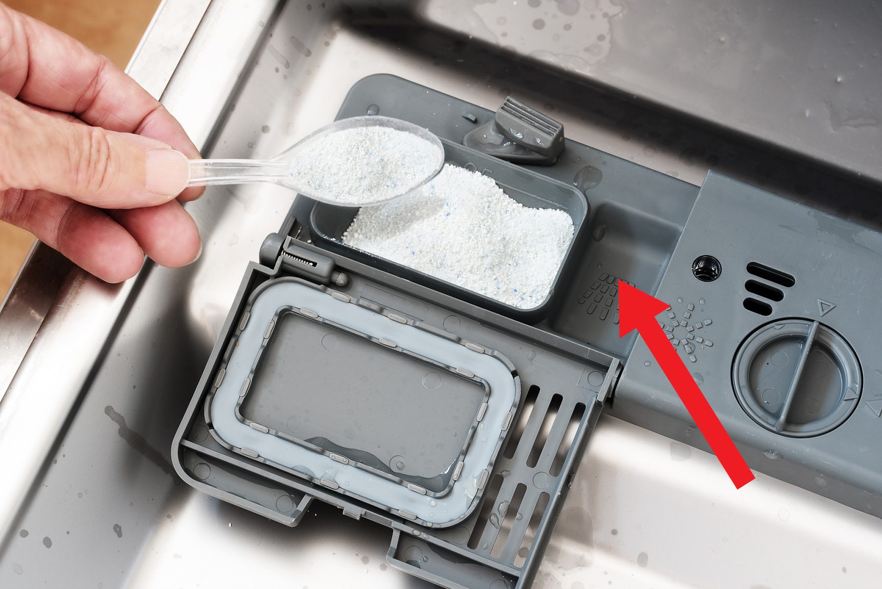 Hand is pouring white washing powder into a dishwasher