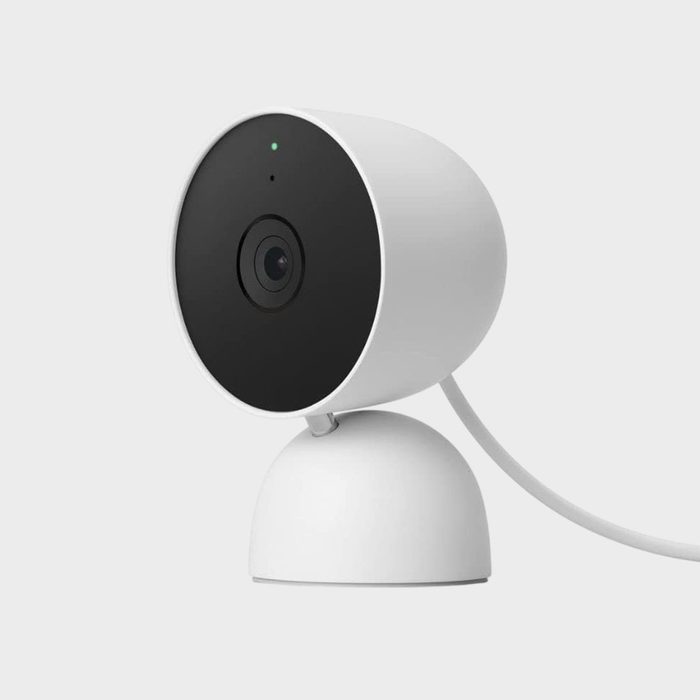 A white security camera is angled slightly upward with a visible cable, set against a plain gray background.