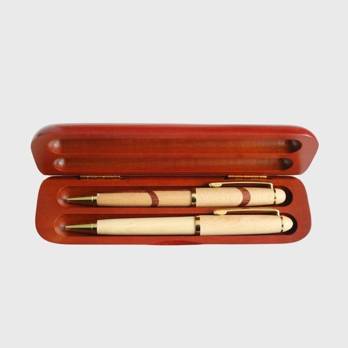 Wooden pens resting inside an open, red wooden case, set against a plain background.