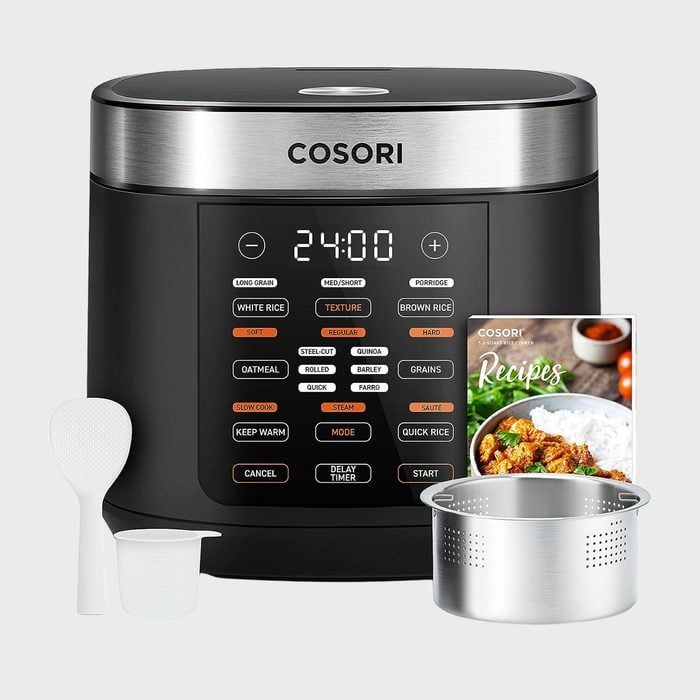 Rice cooker displays digital timer with rice cooking options, surrounded by a spoon, measuring cup, steamer basket, and recipe booklet.