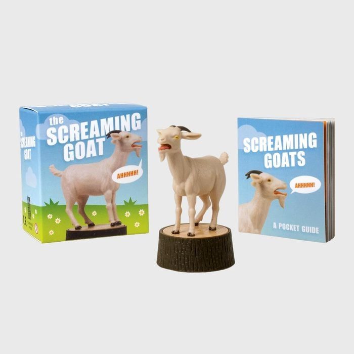 A plastic goat stands on a stump, surrounded by its packaging box and a pocket guide titled 