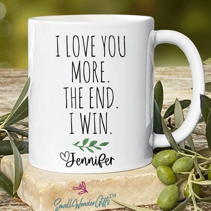 Mug sits on a wooden surface, displaying text 