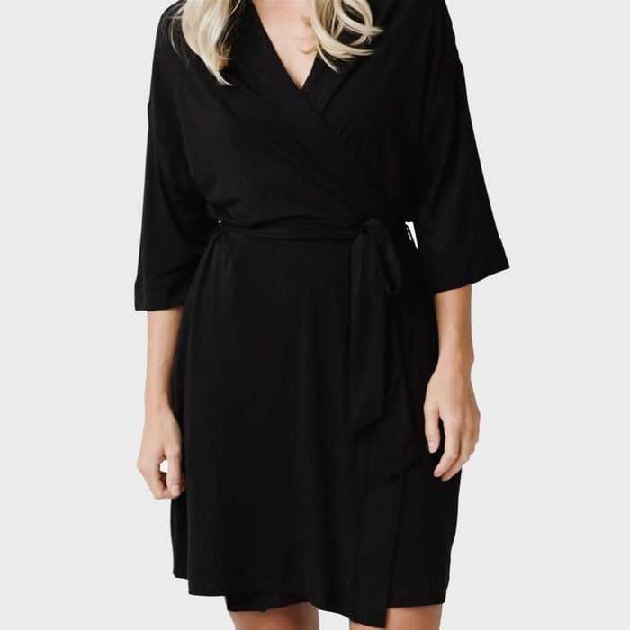 Black wrap dress tied at the waist, worn by a person against a plain gray background.