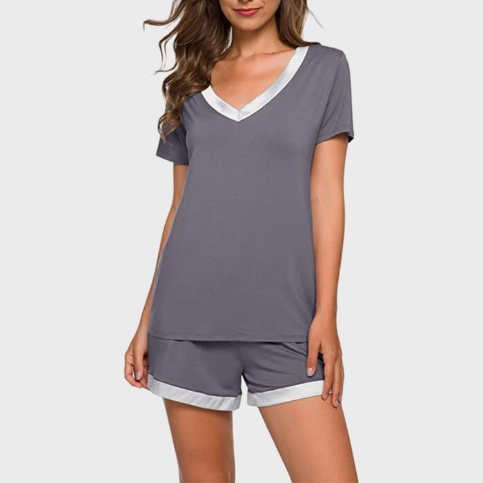 Person models gray pajama set; short-sleeved V-neck top, matching shorts. Plain light gray background.