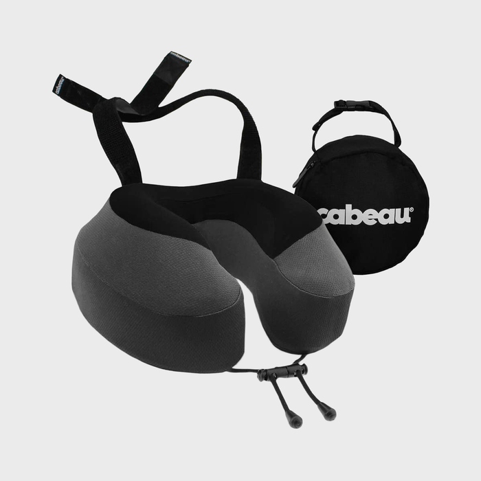 U-shaped travel pillow with adjustable strap; situated beside a round, black storage pouch on a plain background. Text reads 