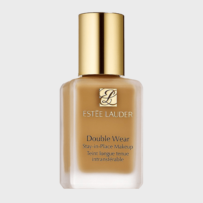 A clear glass bottle with gold cap stands in a plain setting, labeled 
