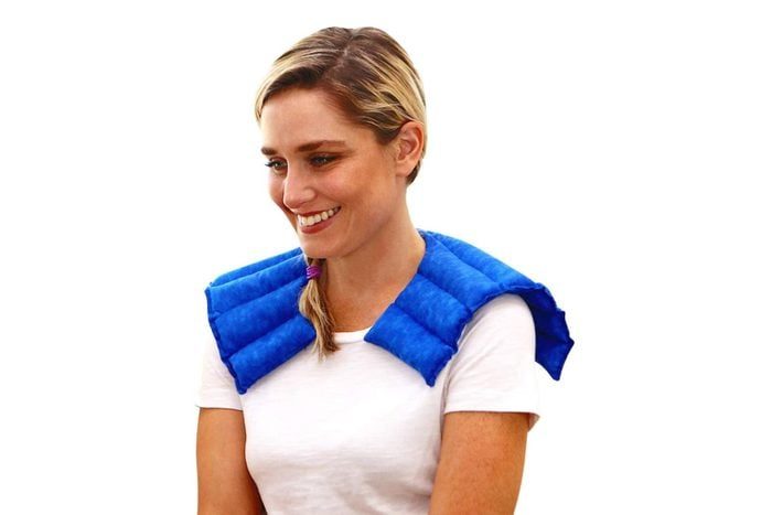 A person wears a blue shoulder wrap, smiling in a relaxed pose, against a plain white background.