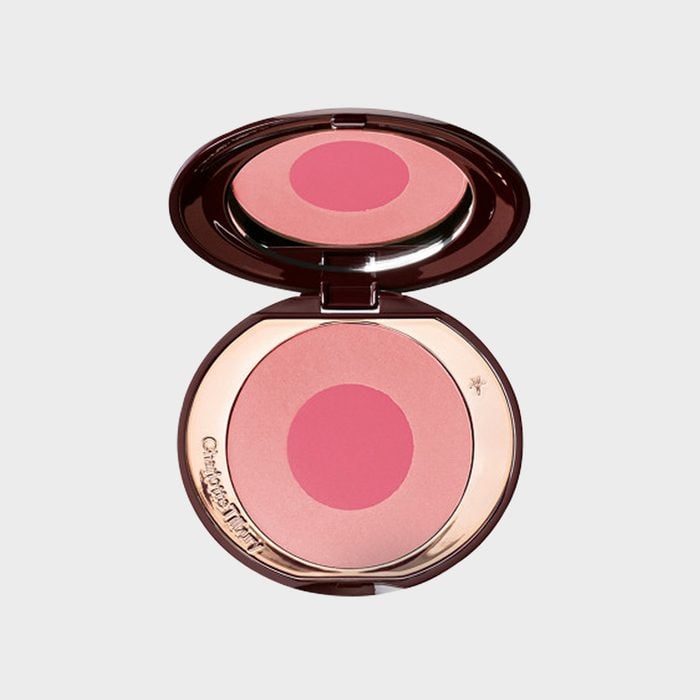 Makeup compact, open, containing two-tone pink blush; mirrored lid reflects blush; text reads 