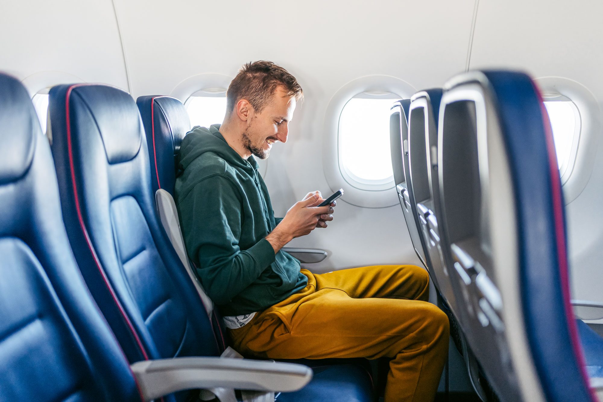 Young Man Using Phone In An Airplane