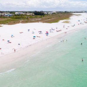Aerial view of a white sand beach with teal water