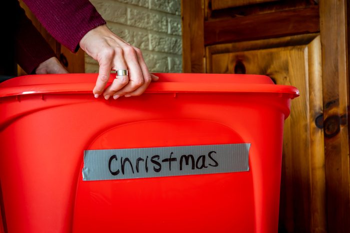 woman holding a red storage bin of christmas holiday decorations