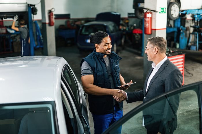 Don't worry, I'll repair your car, shaking hands with car mechanic