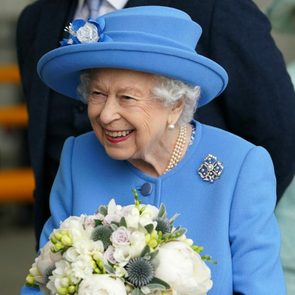 Queen Elizabeth II wearing a blue outfit and holding flowers