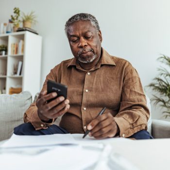 Mature businessman working at home using smart phone
