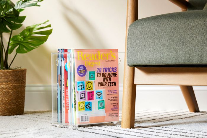magazines gathered and styled in a clear magazine holder near a comfy chair
