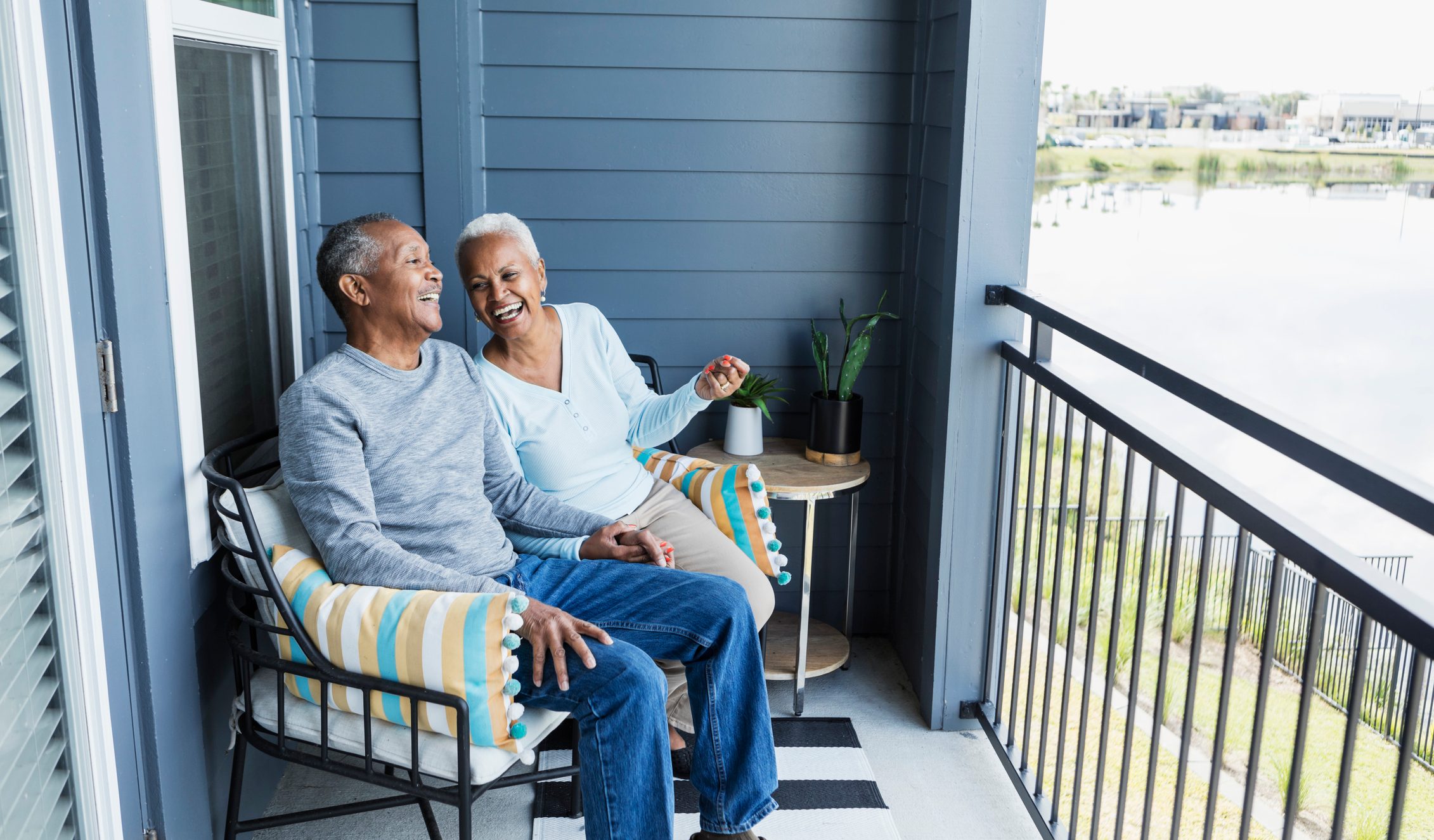 Senior couple relaxing on porch, holding hands, laughing